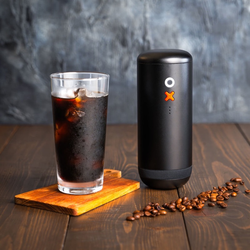Grinding OX Pro beside an iced coffee and coffee beans